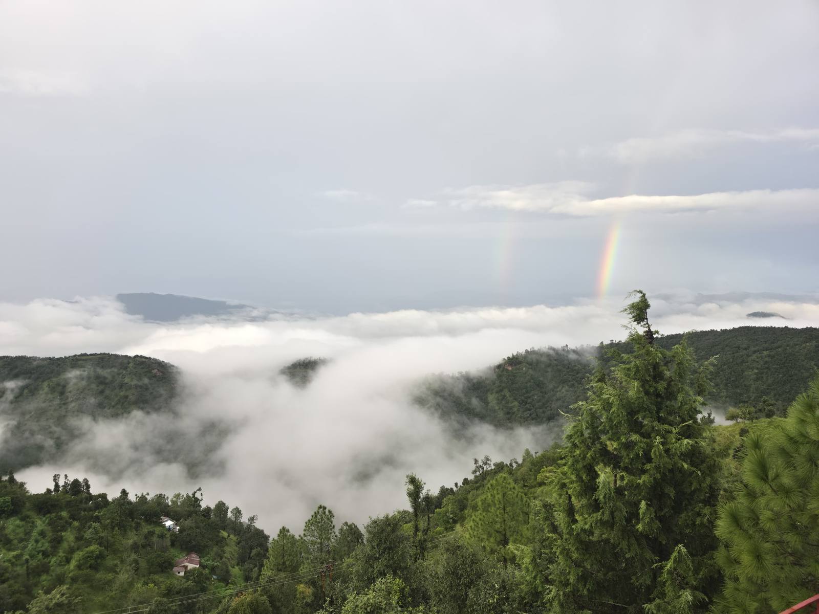 A double rainbow arcing over clouds filling the valley below Hartola